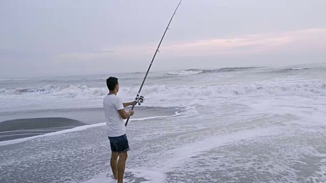 在海洋海滩钓鱼的男人视频素材