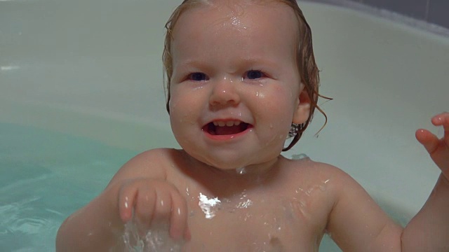 快乐的宝宝笑着掉进浴室的水里视频素材