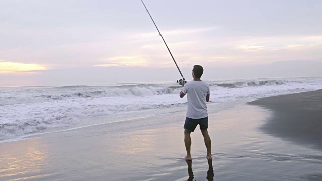 一名男子早晨在海洋海滩钓鱼视频素材