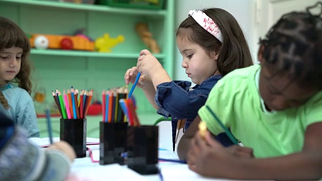 学龄前儿童在幼儿园教室里画画视频素材