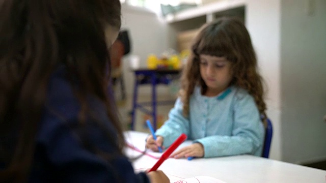 学前班的女孩在课桌上涂鸦视频素材