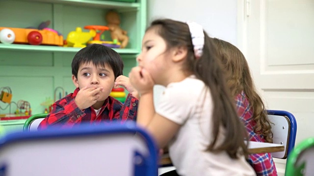 幼儿园小朋友坐在教室里的课桌前视频素材