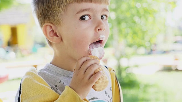 一个三岁的小男孩正在吃装在华夫饼杯里的冰淇淋视频素材