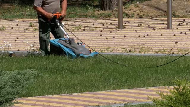 工作的园丁用电动割草机割草视频素材