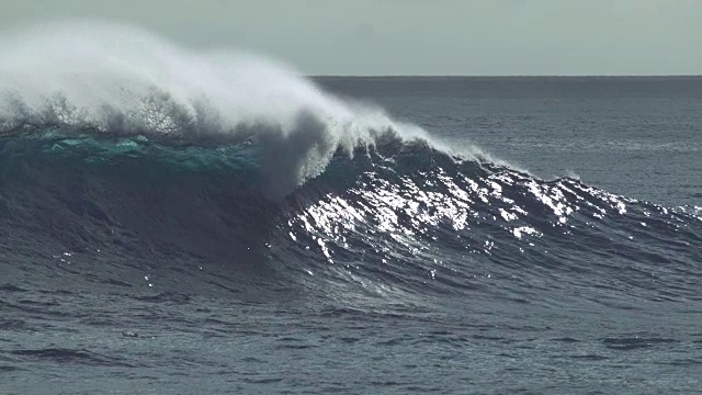 慢镜头:巨大的卷曲的海浪在夏日的阳光下闪闪发光。视频素材