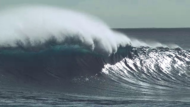 慢镜头:翠绿色的海浪在黑色的岩石海岸附近疯狂地溅起水花。视频素材