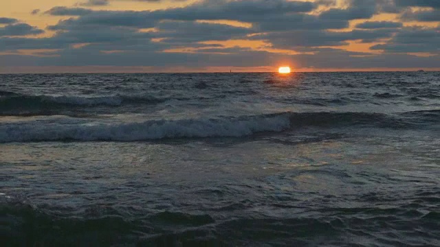 美丽的日落在海滩上，惊人的颜色，光束透过云景在海景。海上日落。日出在海滩。日落海滩。在海上日落。海上日出。慢动作视频素材