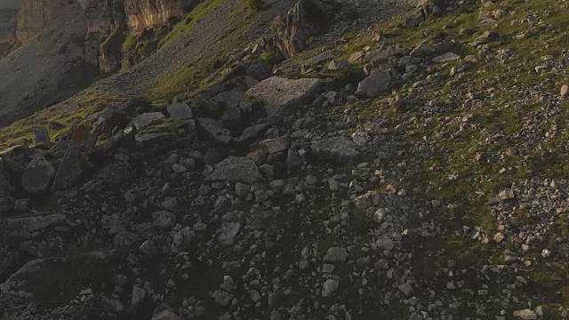 沿着岩石悬崖飞行在山脚下的史诗峭壁的高原在北高加索。以4k / 100mbps的速度飞过布满石头的绿色田野视频素材
