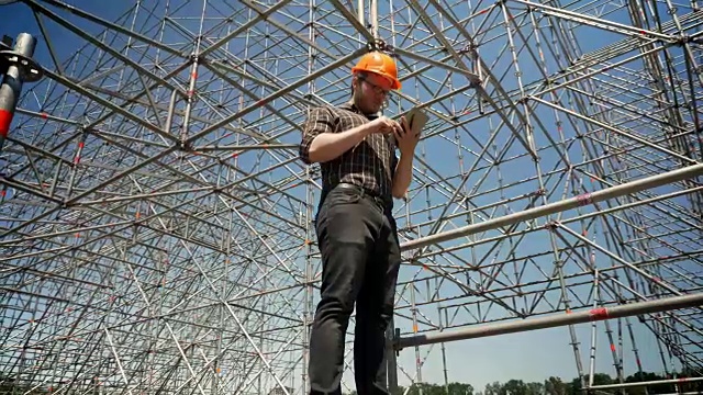 年轻的建筑师站在石板上，看着背景上的金属装置，规划和设计新的项目视频素材