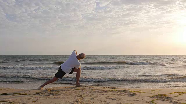 在日落的海滩上运动的男人练习瑜伽体式视频素材