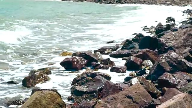 夏天，海浪把海水冲到岩石滩上。近距离看，海浪拍打着海滩。美丽的海浪拍打着石滩视频素材