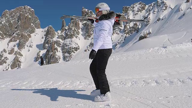 在高山滑雪胜地，一名滑雪者肩上扛着下坡滑雪板前进视频素材