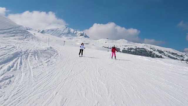 两名女子滑雪者在冬季沿着理想的山坡滑雪视频素材