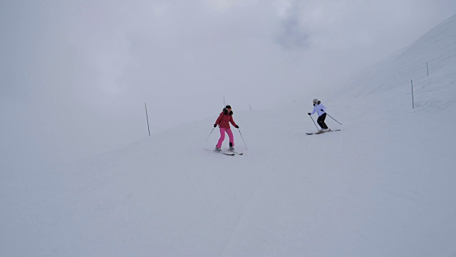 两名女子滑雪者在冬季山坡上同步转弯雕刻滑雪视频素材