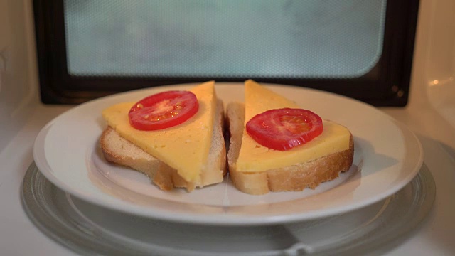 用微波炉加热食物。用微波炉烹饪芝士三明治视频素材