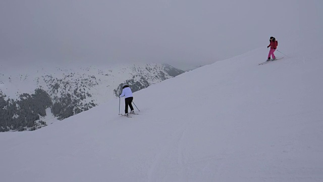 两个运动女滑雪者在冬季滑雪下山视频素材