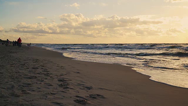 日落在海浪和沙滩上的云后面视频素材