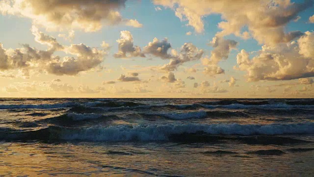 日落在海浪和沙滩上的云后面视频素材