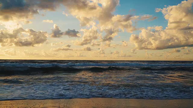 日落在海浪和沙滩上的云后面视频素材