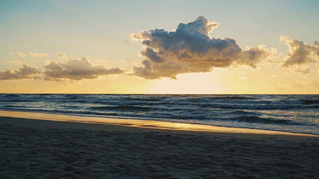 日落在海浪和沙滩上的云后面视频素材