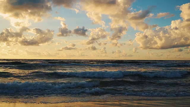 日落在海浪和沙滩上的云后面视频素材