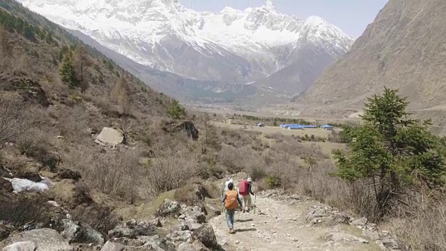 导游带领的游客正在尼泊尔马纳斯鲁地区的喜马拉雅山徒步旅行。视频素材