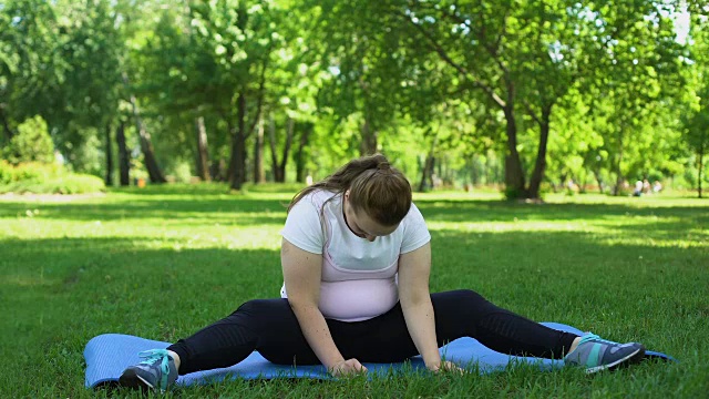 胖女孩笨拙地在户外做燃烧脂肪的运动，疲惫、失望视频素材