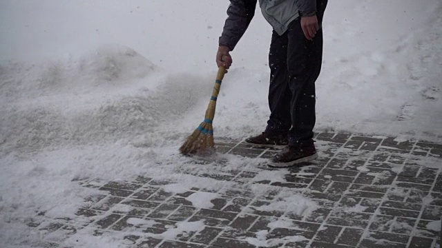 那个不知名的人清扫街上的积雪。缓慢的运动。视频素材