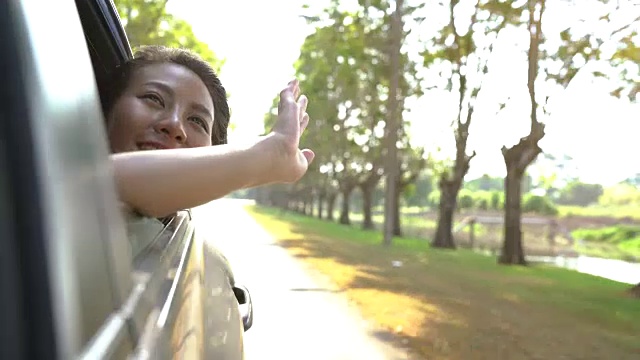 年轻的亚洲女子喜欢感觉风透过车窗。视频素材