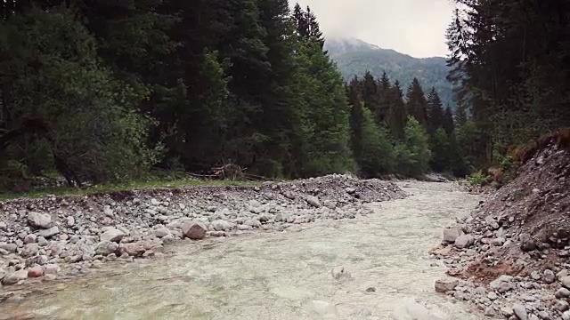 山河流淌的背景是群山和绿色的森林。视频素材