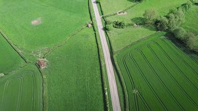 鸟瞰图沿着英国乡村的乡村道路飞行，一辆汽车沿着它行驶视频素材