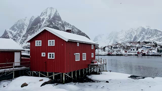 挪威罗浮敦群岛勒内(Reine)的北极海岸线上有雪和山的红色房子视频素材