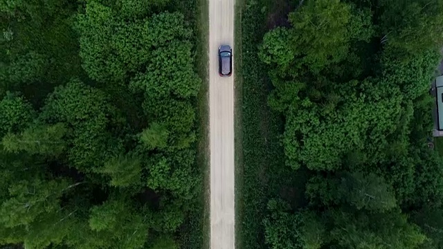 村里的路。汽车沿着树木和房屋之间的道路行驶。视频素材