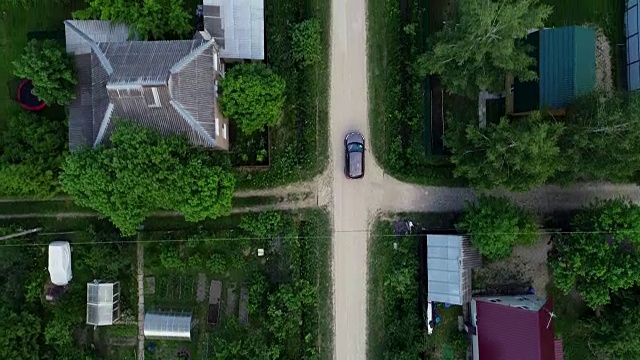 村里的路。汽车沿着树木和房屋之间的道路行驶。视频素材