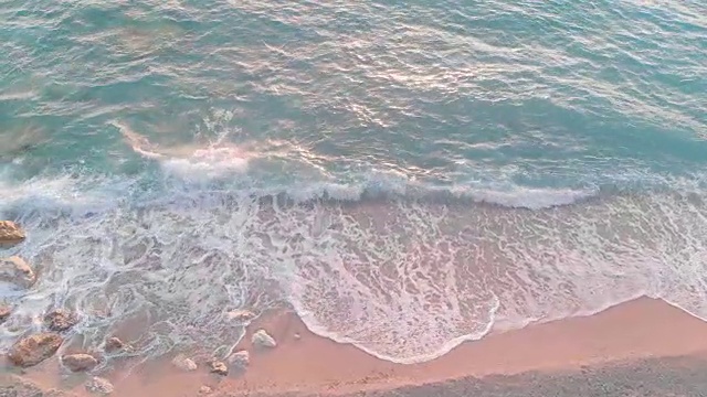 日落时分，海浪拍打着布满岩石的海滩。空中无人机视图视频素材