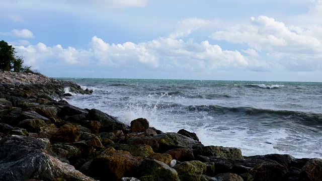 夏天，海浪把海水冲到岩石滩上。近距离看，海浪拍打着海滩视频素材