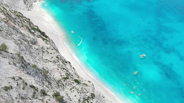 鸟瞰图的岩石悬崖和海浪冲击的沙滩视频素材