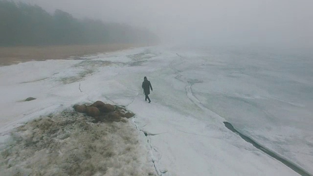 孤独的人走过冰天雪地的海岸线视频素材