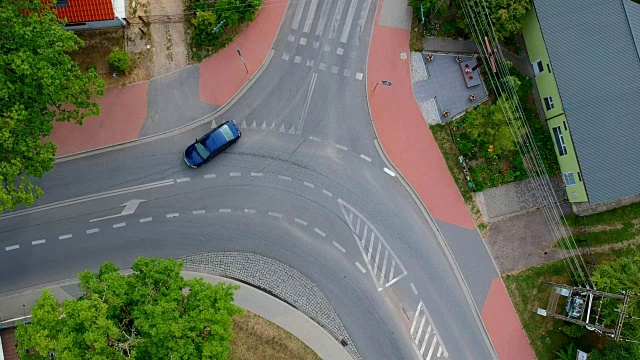 一辆蓝色的汽车正行驶在城市的十字路口，鸟瞰图视频下载