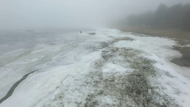 孤独的人走过冰天雪地的海岸线视频素材