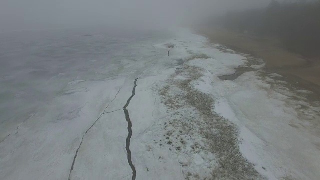 孤独的人走过冰天雪地的海岸线视频素材