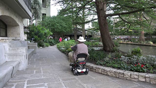 圣安东尼奥的一名男子骑着滑板车沿河而上视频素材