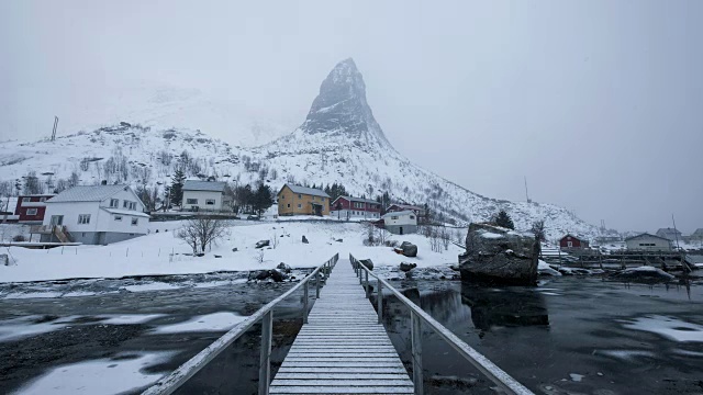 在斯堪的那维亚村庄的著名山景背景木桥上的暴风雪的延时拍摄视频素材