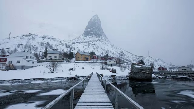 延时放大的暴风雪在木桥上与著名的山背景在斯堪的纳维亚村庄视频素材