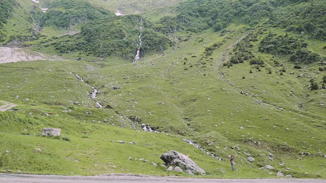 一位年轻的女性徒步旅行者带着照相机爬山。罗马尼亚喀尔巴阡山脉的transagarasan视频素材