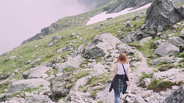 一位年轻的女性徒步旅行者带着照相机爬山。罗马尼亚喀尔巴阡山脉的transagarasan视频素材