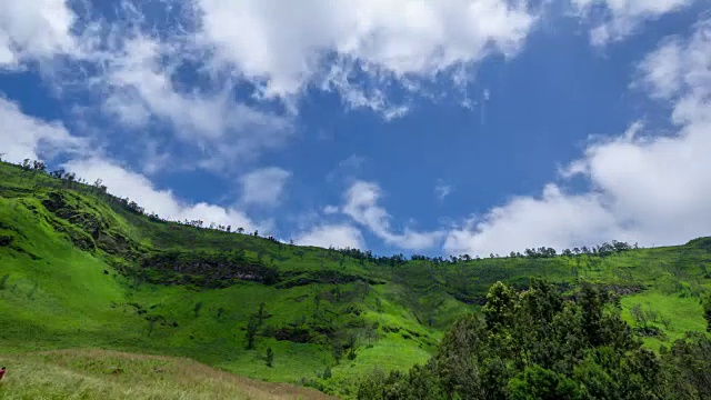 4K移动云在Bromo大草原上空的时间间隔，这是一个绿色的丘陵地区，全年看起来都是绿色的。放大。视频素材