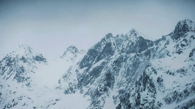 在阴沉的冬天里，延时平移带有暴风雪的山顶视频素材