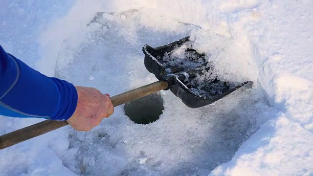 冰钻洞的特写在冰上为冬季捕鱼和铲清理雪视频素材