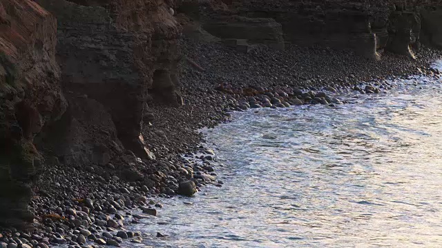 海浪拍打着悬崖下的石滩视频素材